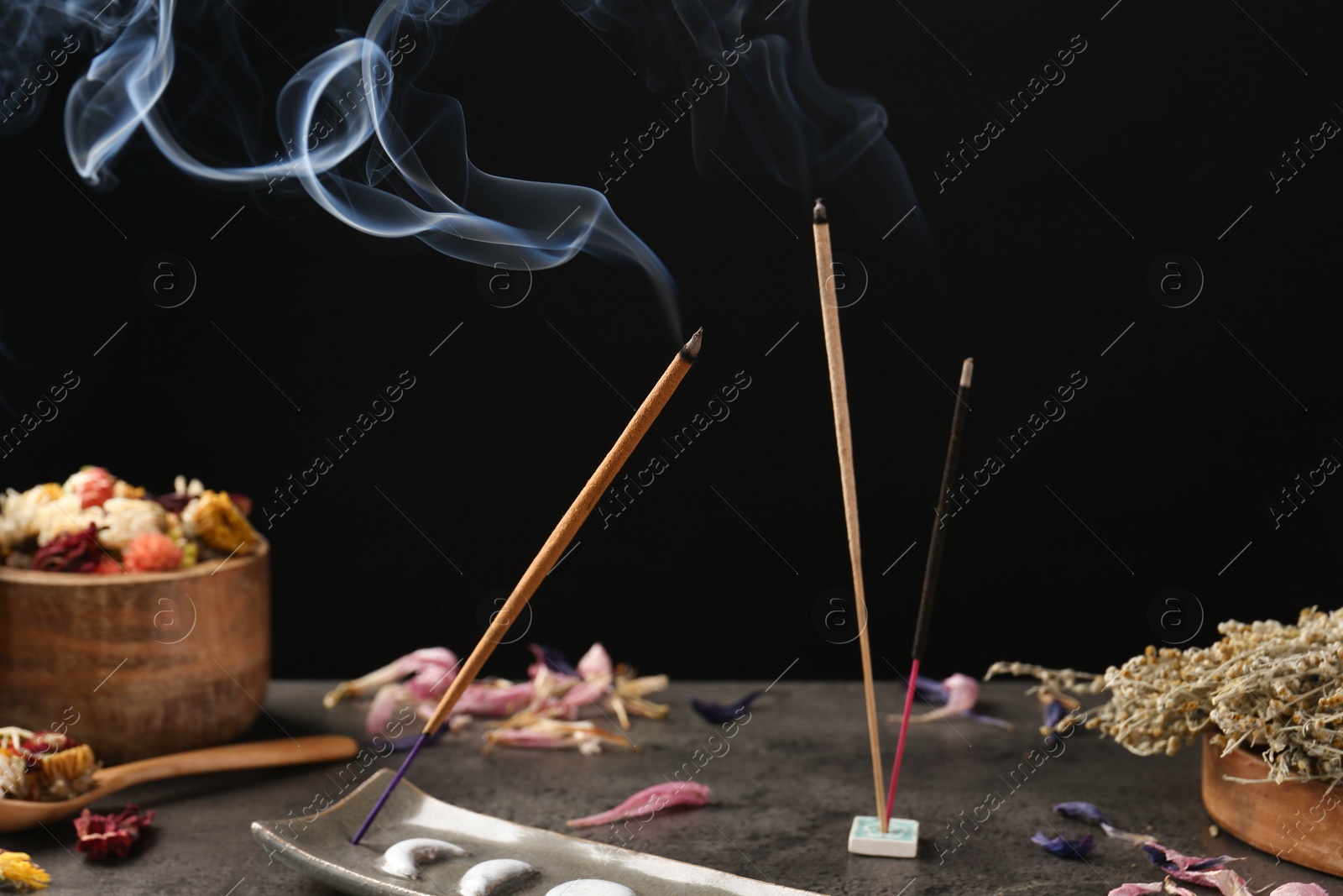 Photo of Aromatic incense sticks smoldering on grey table