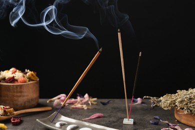 Photo of Aromatic incense sticks smoldering on grey table