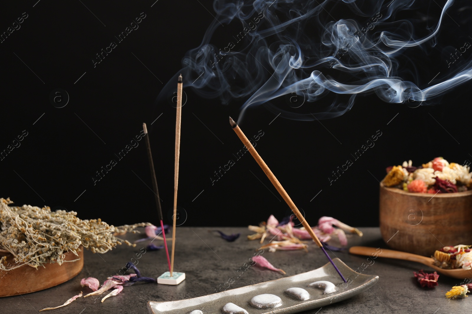 Photo of Aromatic incense sticks smoldering on grey table