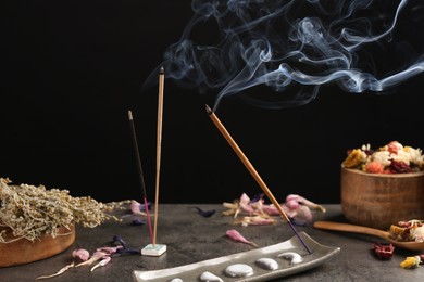 Photo of Aromatic incense sticks smoldering on grey table