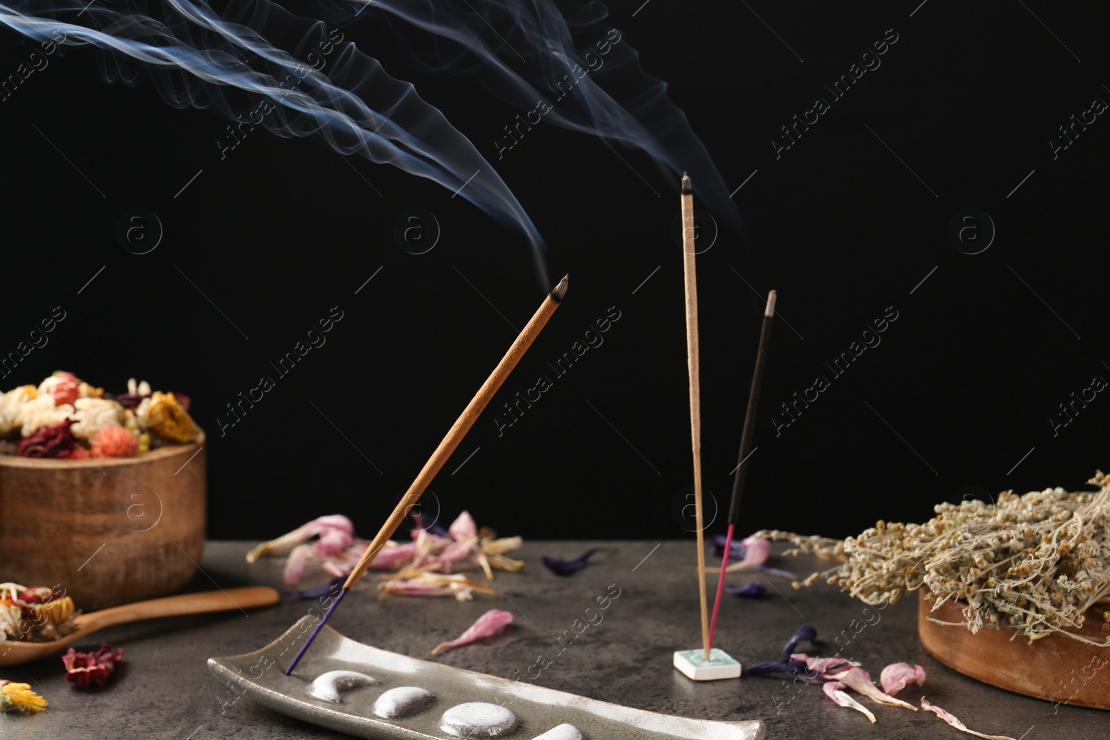 Photo of Aromatic incense sticks smoldering on grey table