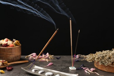 Photo of Aromatic incense sticks smoldering on grey table