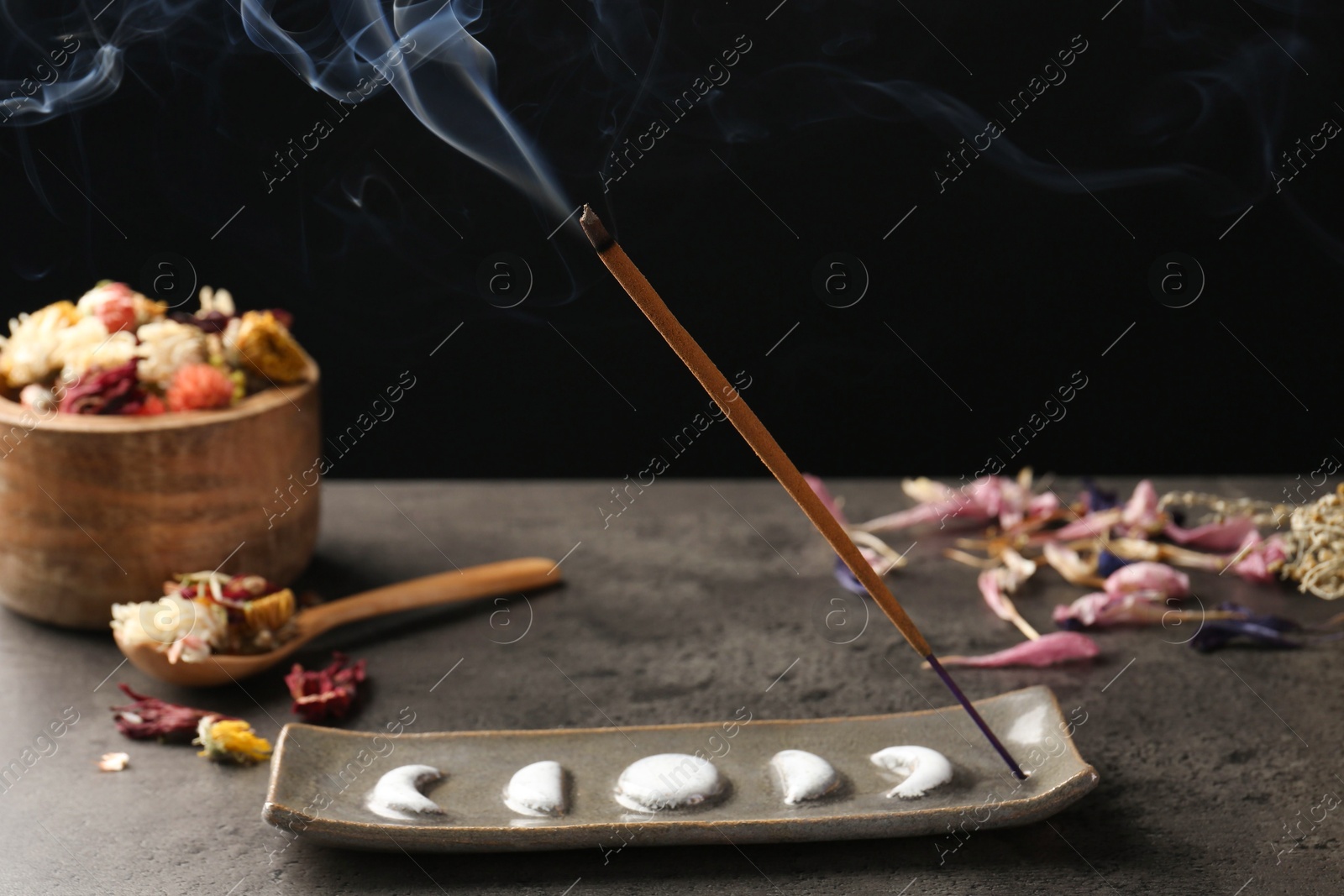 Photo of Aromatic incense stick smoldering on grey table