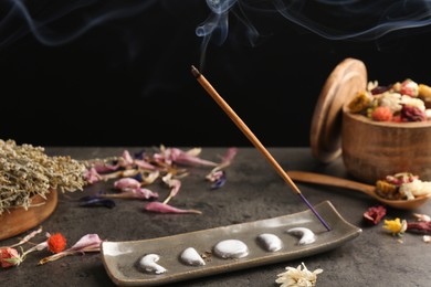 Photo of Aromatic incense stick smoldering on grey table