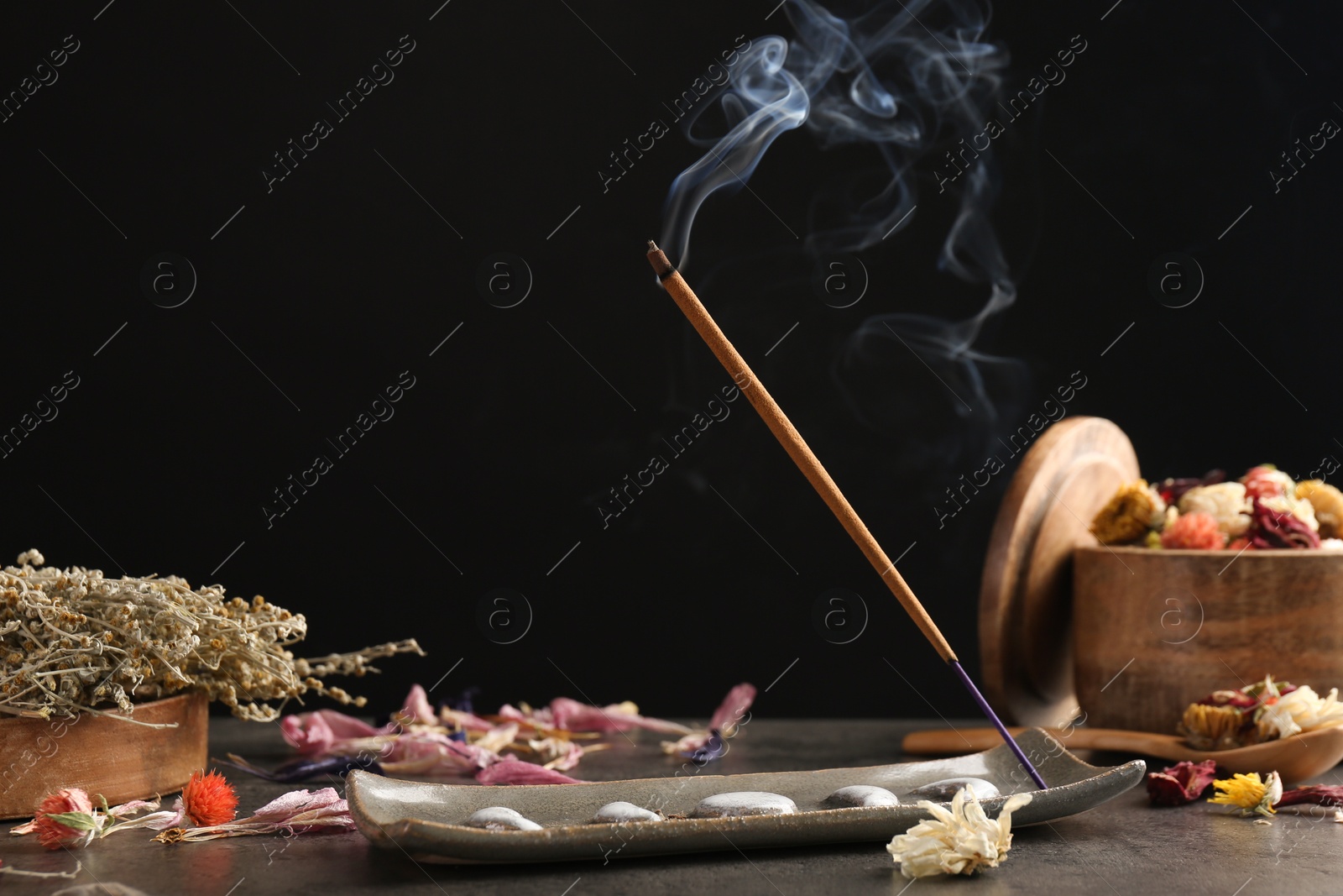 Photo of Aromatic incense stick smoldering on grey table