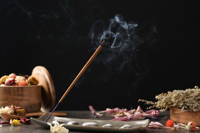 Photo of Aromatic incense stick smoldering on grey table