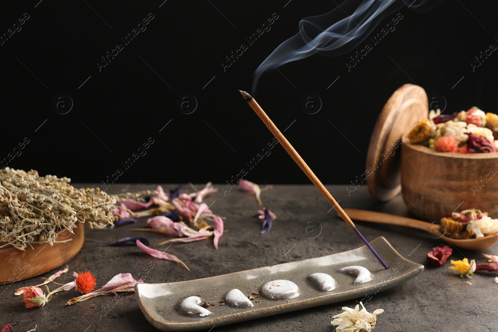 Photo of Aromatic incense stick smoldering on grey table