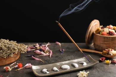 Aromatic incense stick smoldering on grey table