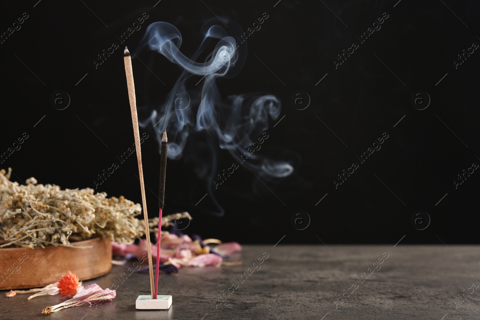 Photo of Aromatic incense sticks smoldering on grey table. Space for text