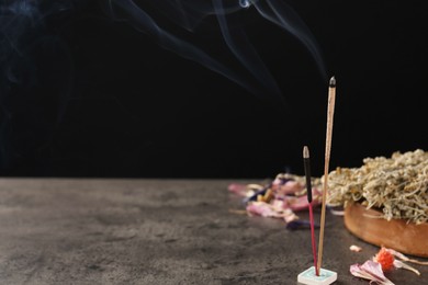 Aromatic incense sticks smoldering on grey table. Space for text