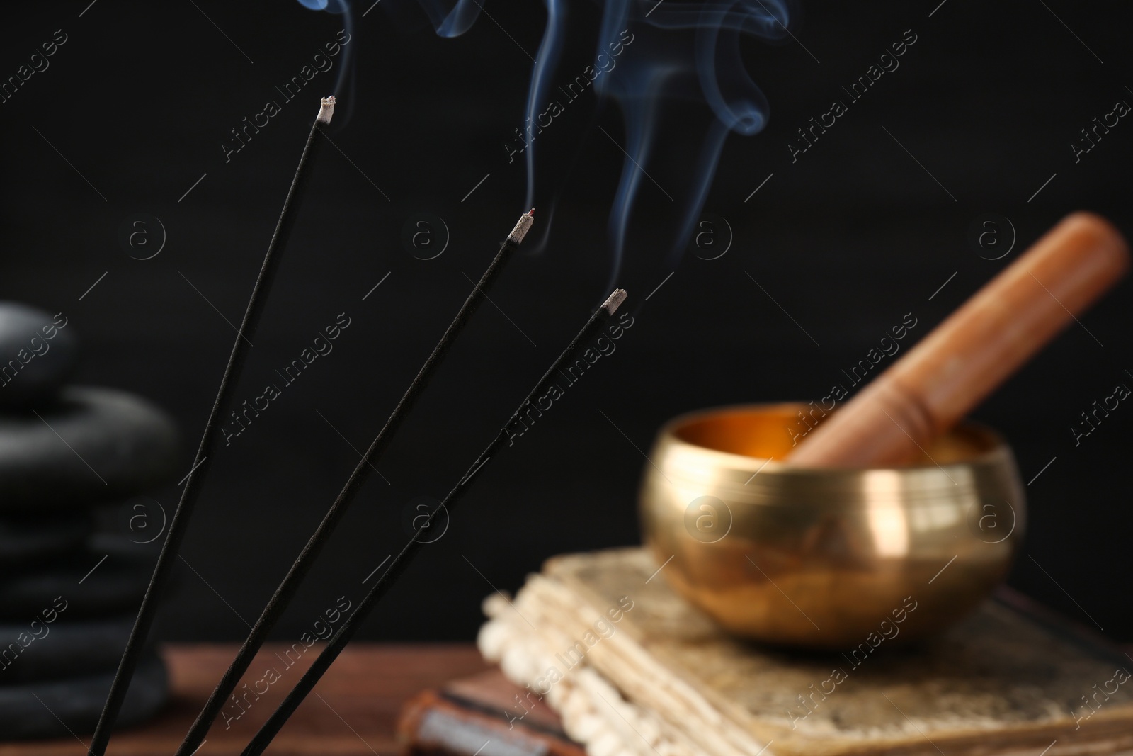 Photo of Aromatic incense sticks smoldering on blurred background, closeup