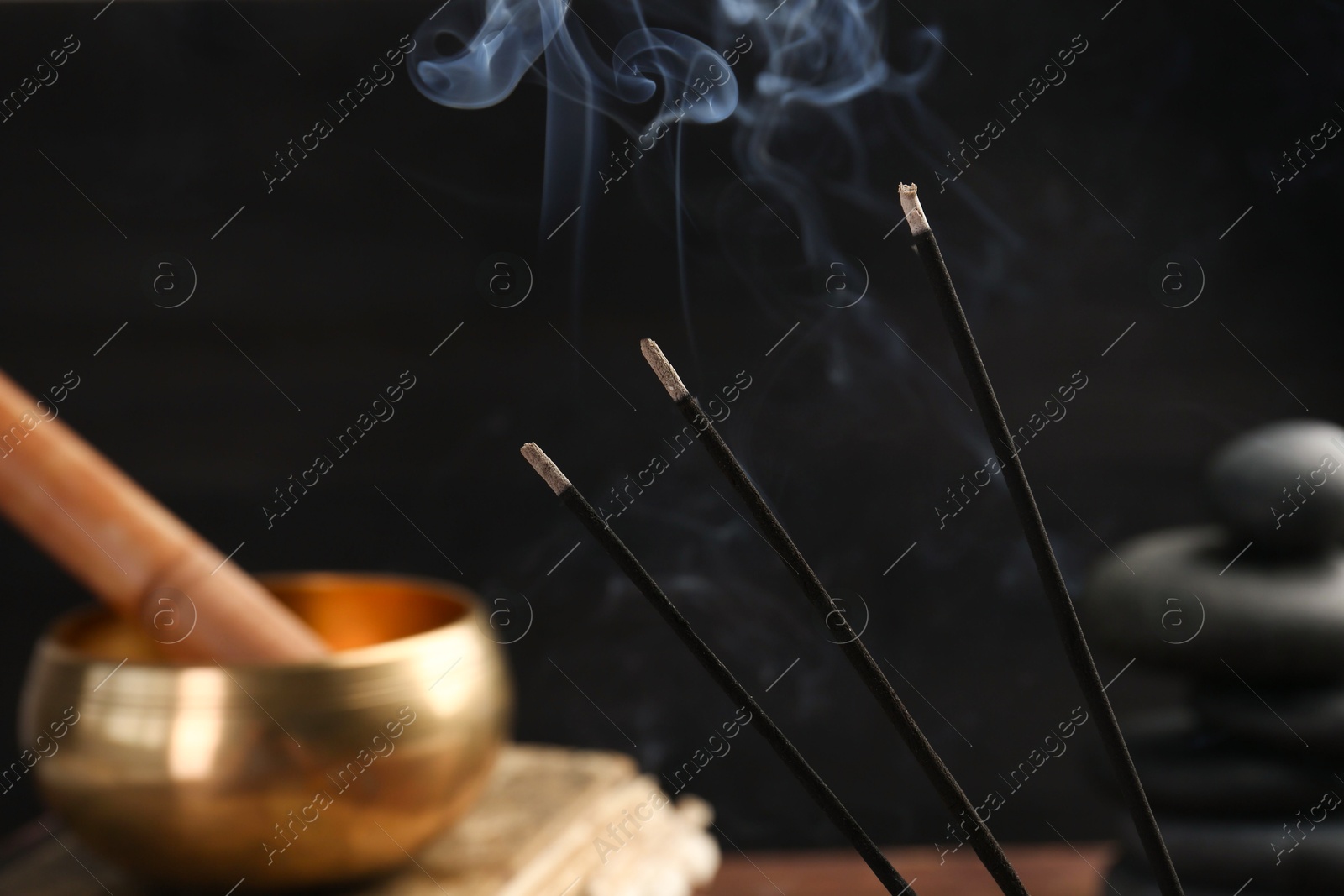 Photo of Aromatic incense sticks smoldering on blurred background, closeup