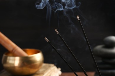 Photo of Aromatic incense sticks smoldering on blurred background, closeup