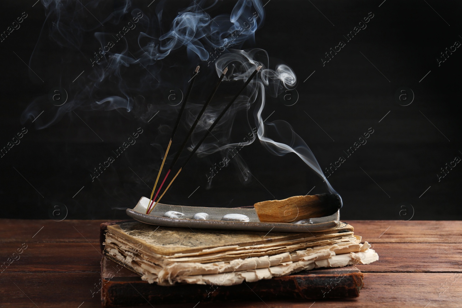 Photo of Aromatic incense sticks smoldering on wooden table