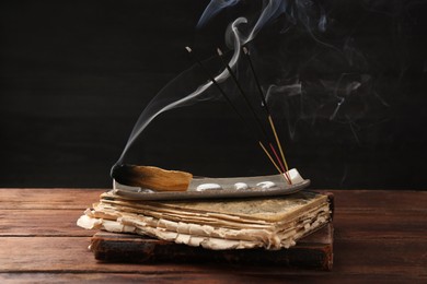 Photo of Aromatic incense sticks smoldering on wooden table