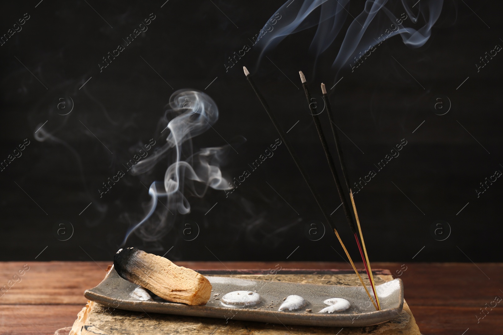 Photo of Aromatic incense sticks smoldering on wooden table