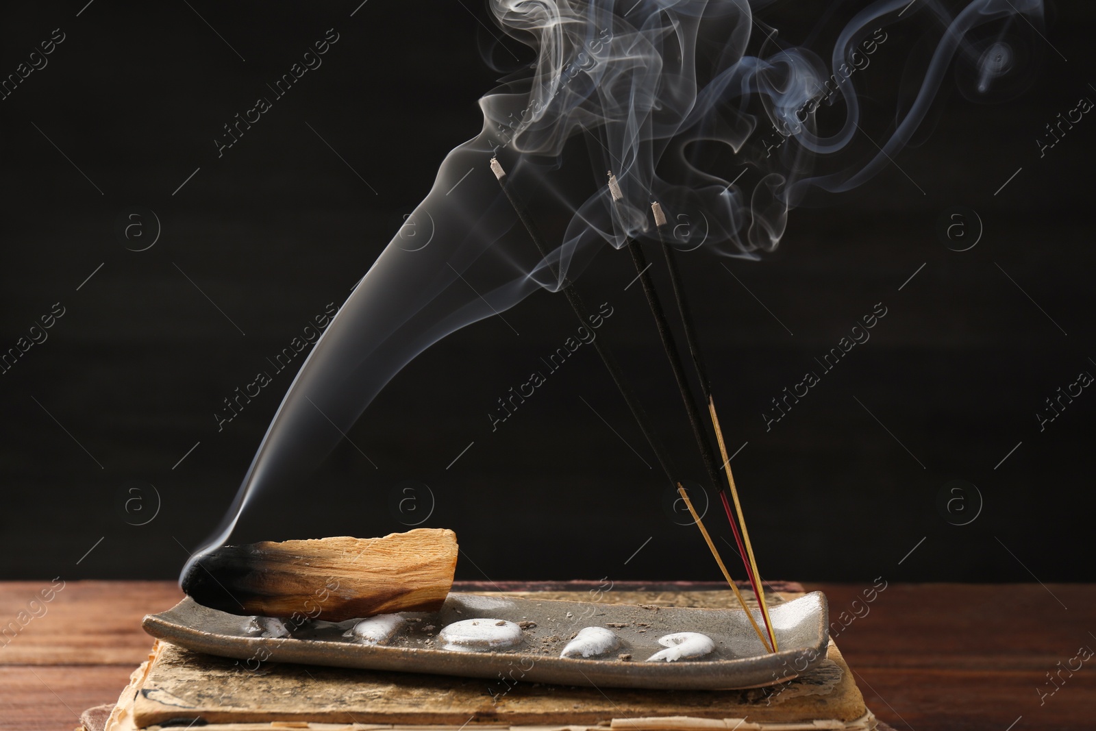 Photo of Aromatic incense sticks smoldering on wooden table