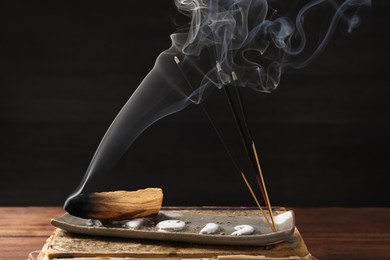 Photo of Aromatic incense sticks smoldering on wooden table