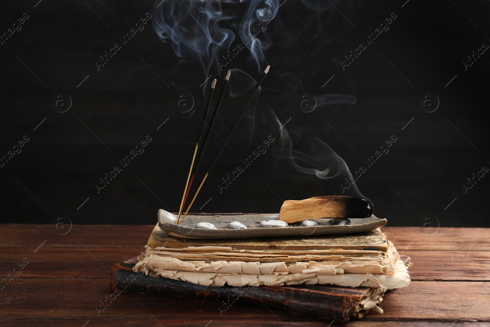 Photo of Aromatic incense sticks smoldering on wooden table