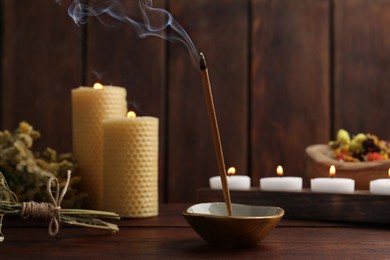 Photo of Aromatic incense stick smoldering on wooden table