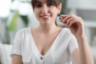 Woman holding SIM card indoors, selective focus