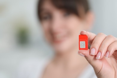 Woman holding SIM card indoors, selective focus