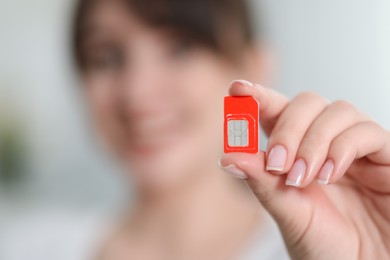 Photo of Woman holding SIM card indoors, selective focus