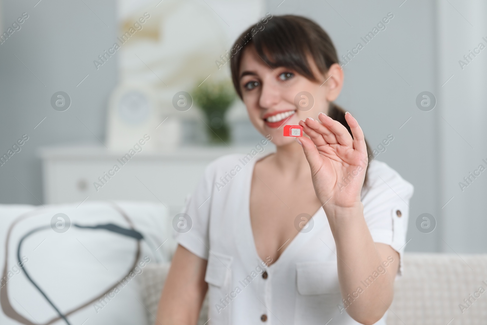 Photo of Woman holding SIM card on sofa at home