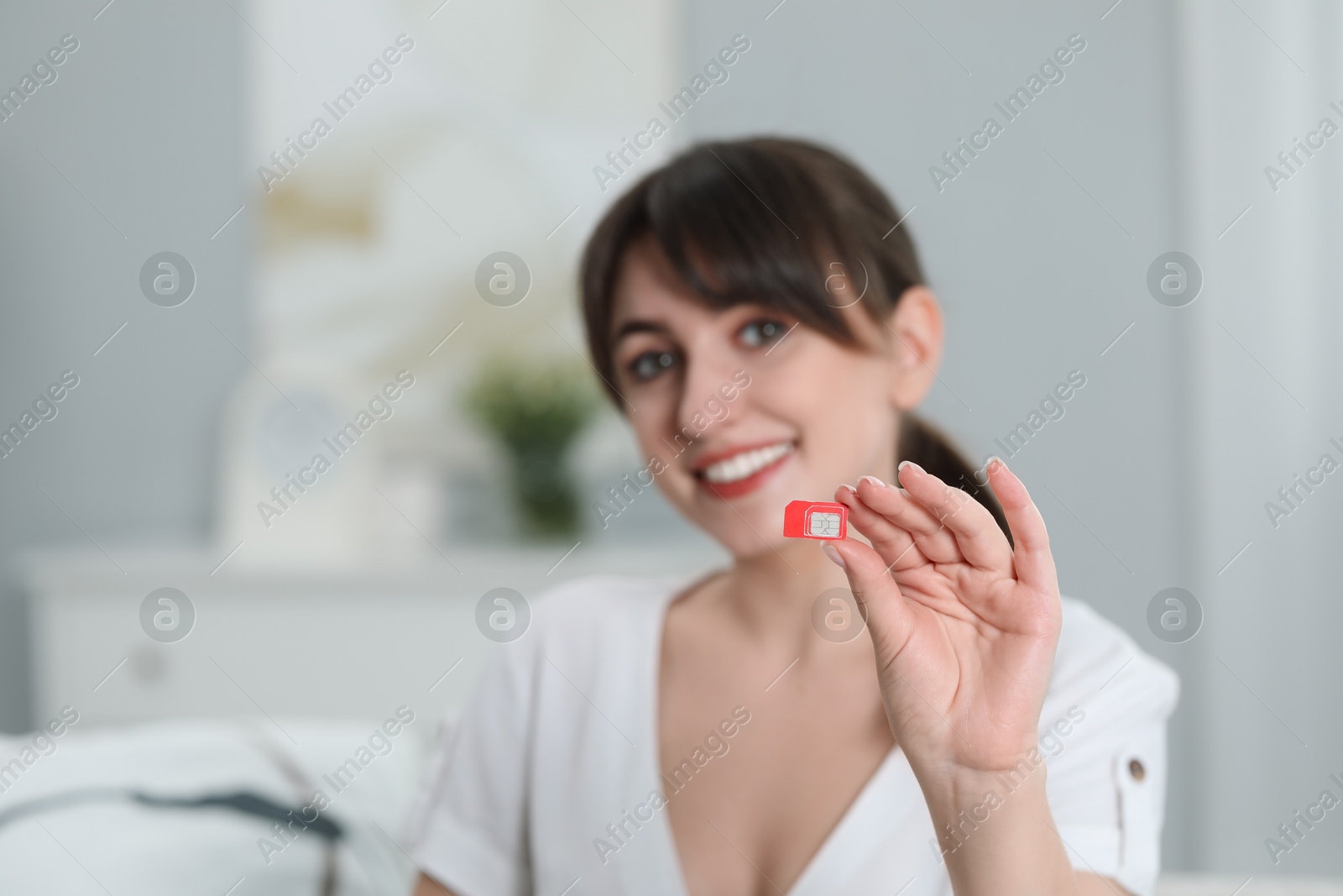 Photo of Woman holding SIM card at home, selective focus