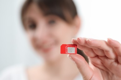 Woman holding SIM card at home, selective focus