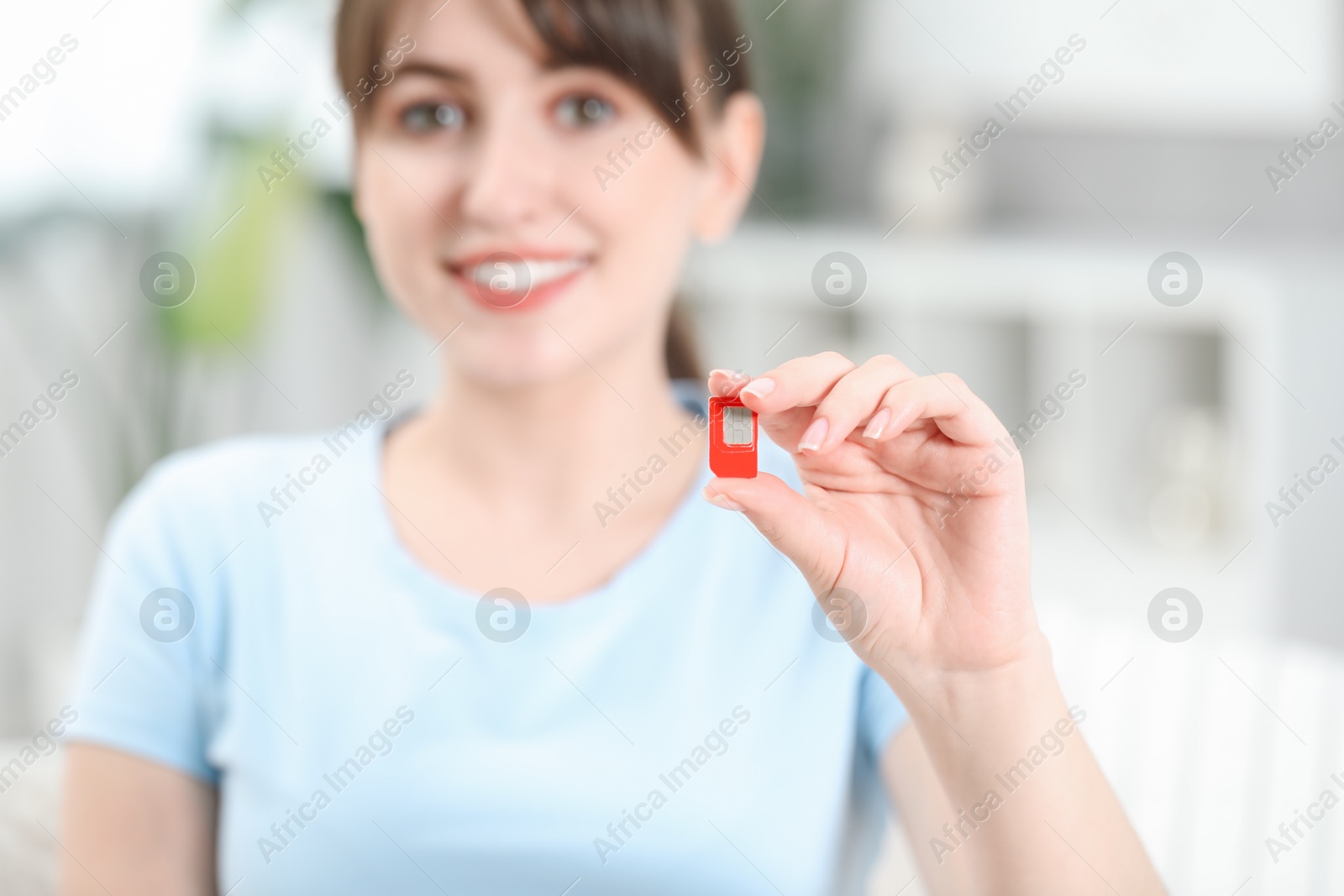 Photo of Woman holding SIM card at home, selective focus