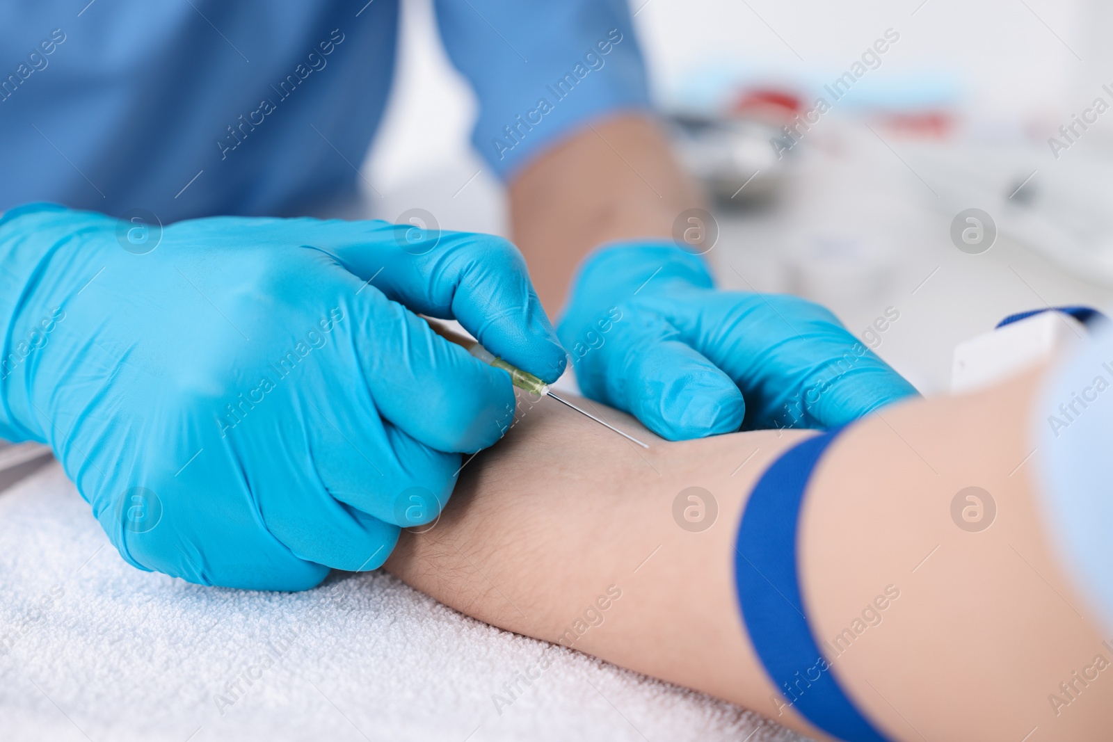 Photo of Nurse inserting IV into arm of patient in hospital, closeup