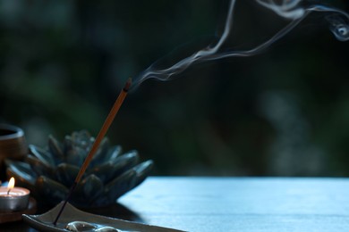 Photo of Incense stick smoldering in holder and burning candle on table outdoors, space for text