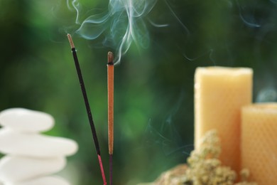 Two incense sticks smoldering against blurred background