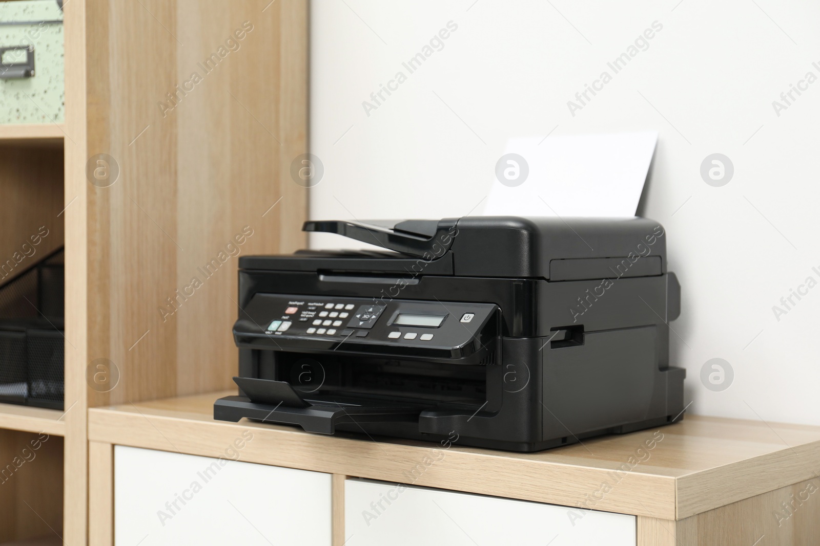 Photo of Modern printer with paper on wooden nightstand in office