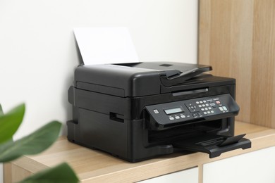 Photo of Modern printer with paper on wooden nightstand in office