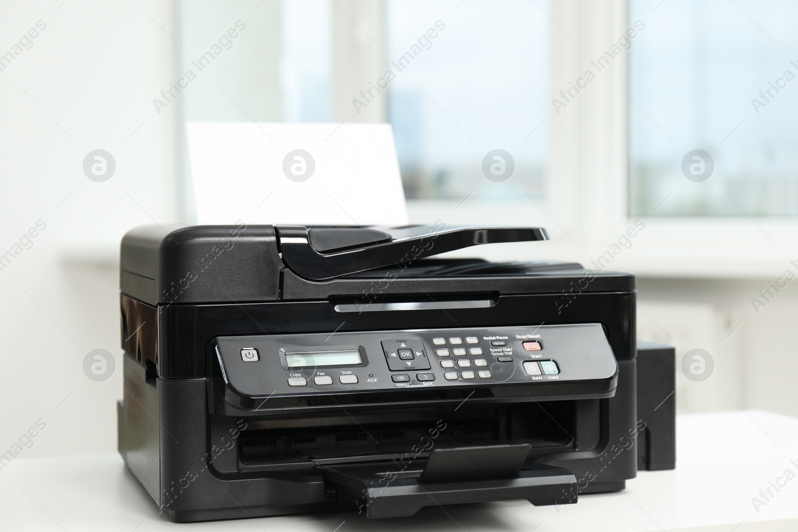 Photo of Modern printer with paper on white table in office