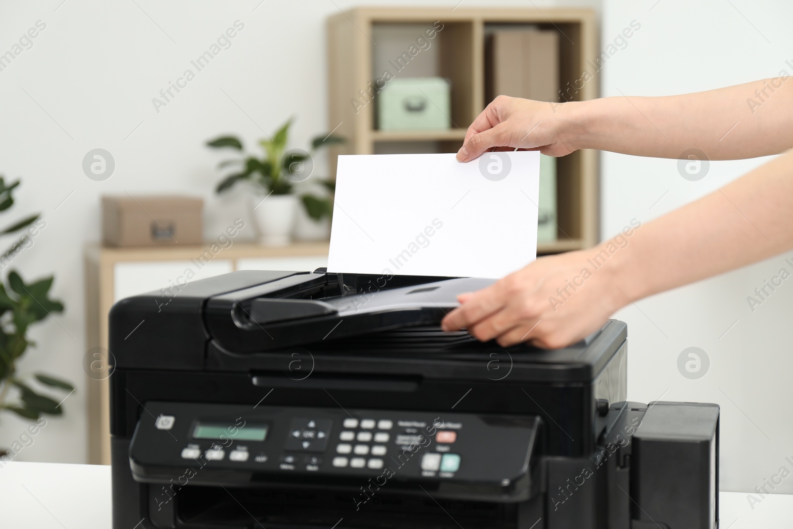 Photo of Woman using modern printer at workplace indoors, closeup