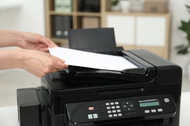 Woman using modern printer at workplace indoors, closeup