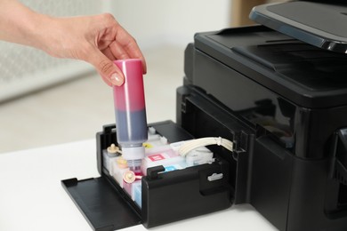 Photo of Woman refilling ink in modern printer at workplace indoors, closeup