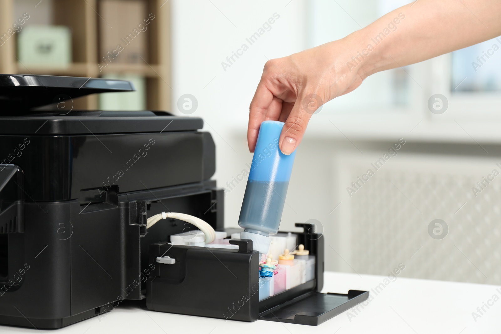 Photo of Woman refilling ink in modern printer at workplace indoors, closeup