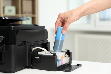 Photo of Woman refilling ink in modern printer at workplace indoors, closeup