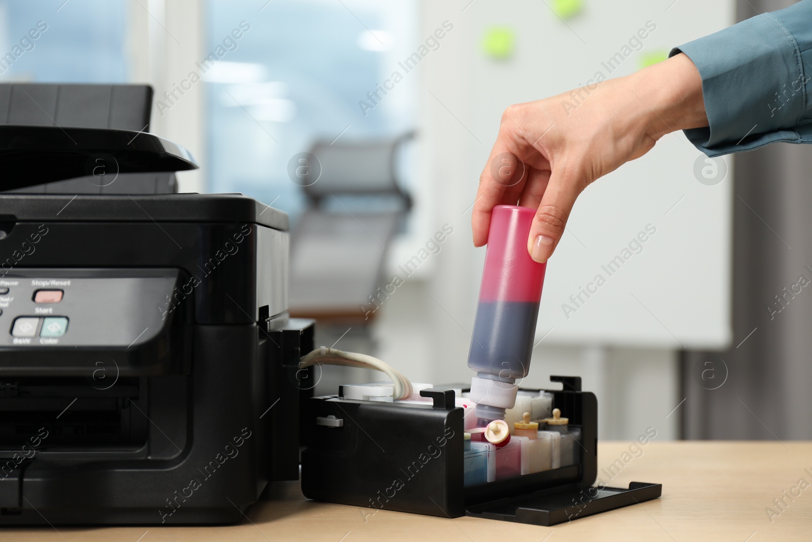 Photo of Woman refilling ink in modern printer at workplace indoors, closeup