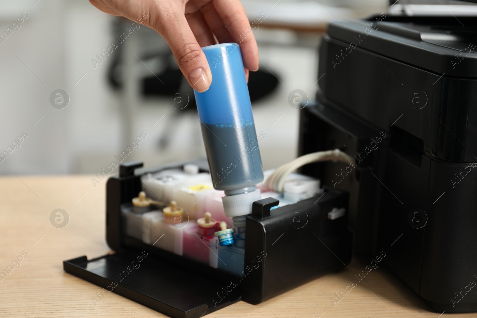 Photo of Woman refilling ink in modern printer at workplace indoors, closeup