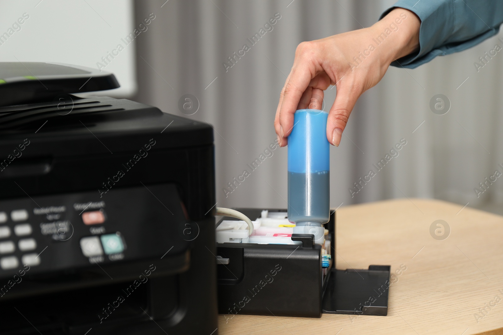 Photo of Woman refilling ink in modern printer at workplace indoors, closeup