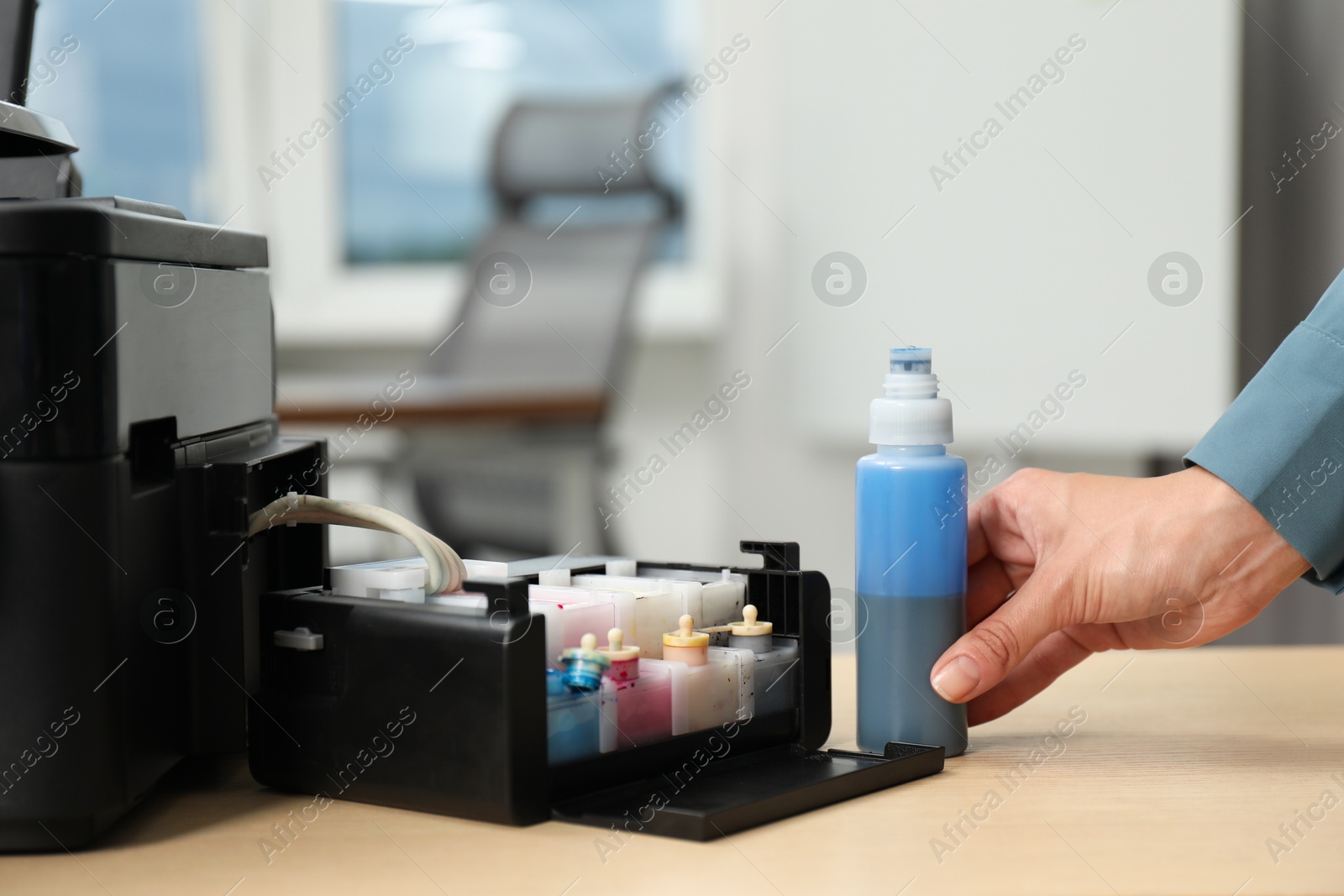 Photo of Woman refilling ink in modern printer at workplace indoors, closeup