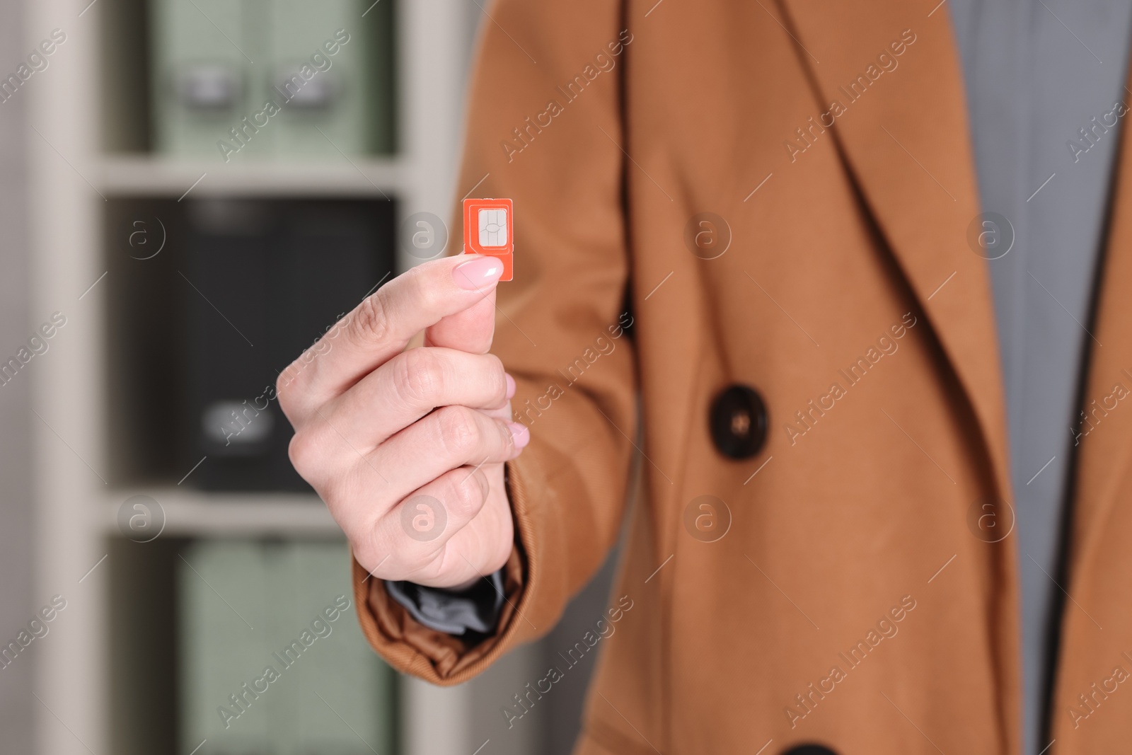 Photo of Woman holding SIM card indoors, closeup view