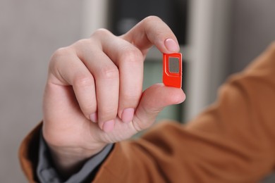 Photo of Woman holding SIM card indoors, closeup view