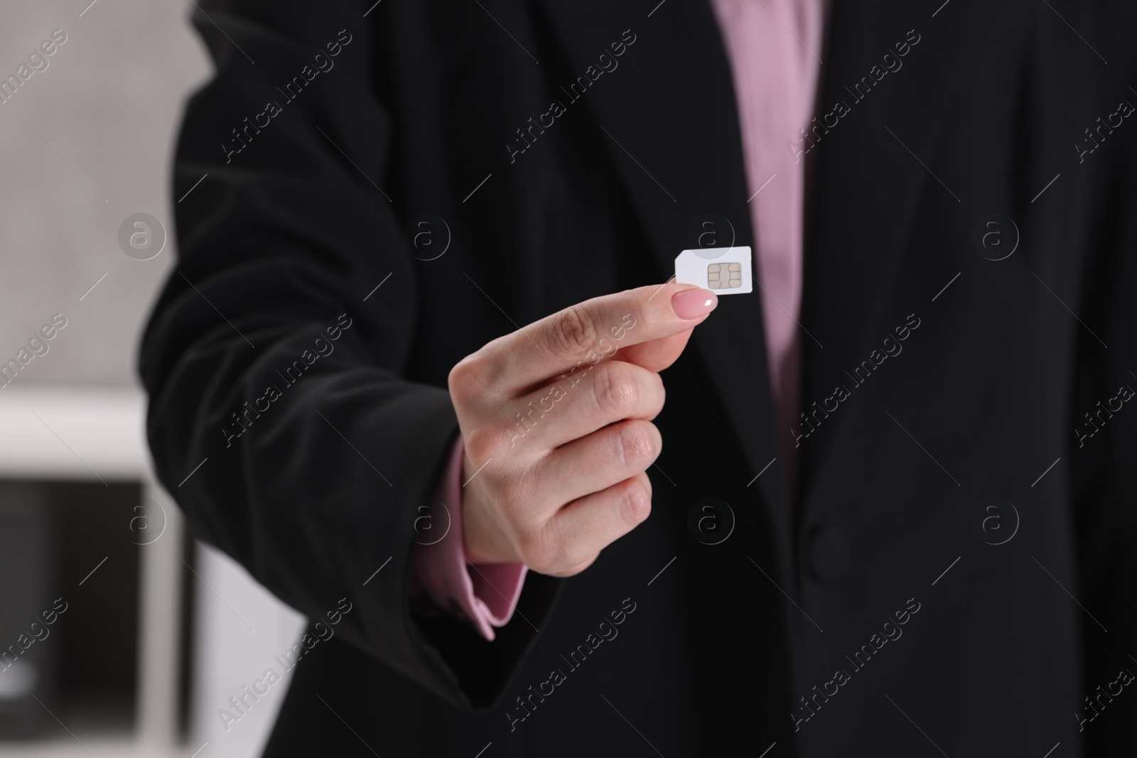 Photo of Woman holding SIM card indoors, closeup view