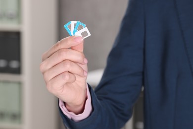 Photo of Woman holding SIM cards indoors, closeup view